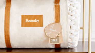 White Bearaby weighted blanket with tan straps on display in a store