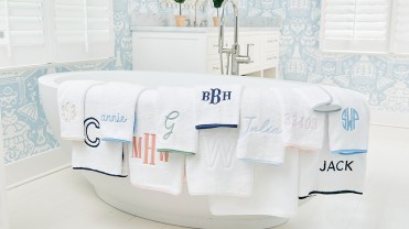 Embroidered towels draped over a white bath tub