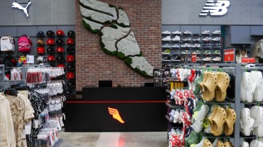 Rows of shows next to a mural in a footwear store.