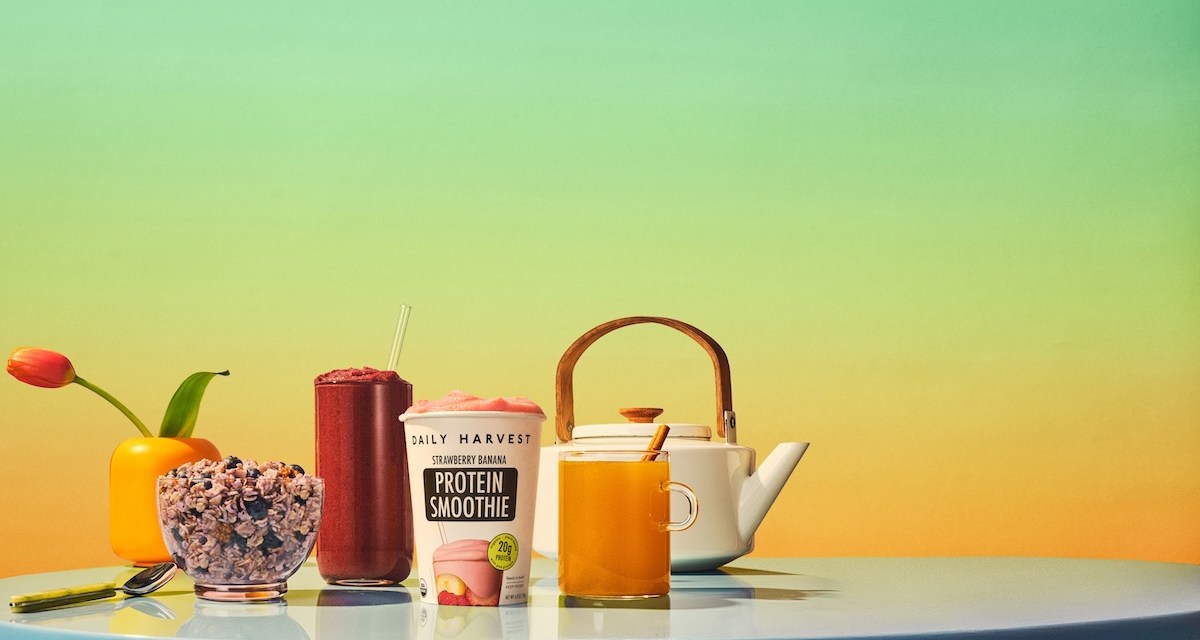 Daily Harvest smoothie, elixir and oat bowl on a blue table against a green and yellow background.